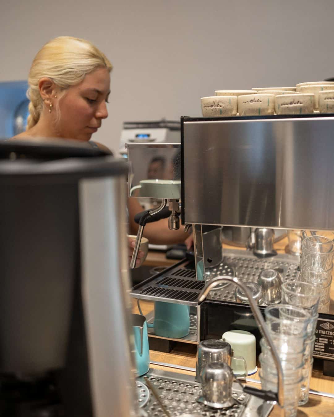 Café fresco en máquina de espresso en Candela Coffee, ambiente acogedor y moderno.