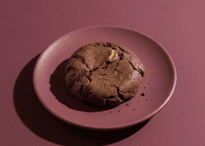 Galleta de chocolate en plato rosa sobre fondo rosa.
