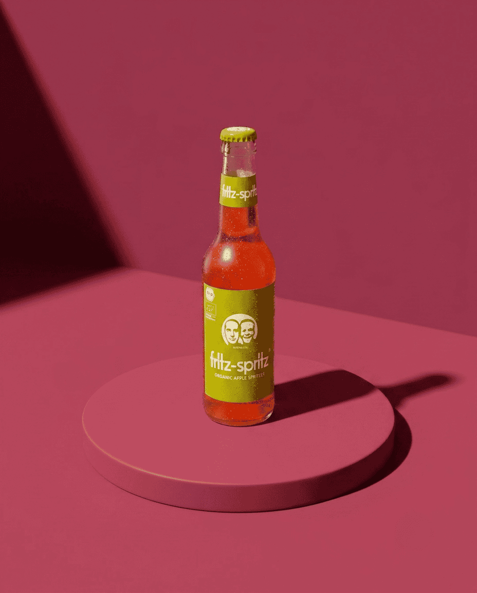 Fritz Candela Rolls Studio 5 Botella de zumo Fritz-Spritz en fondo rosa, producto saludable y refrescante.