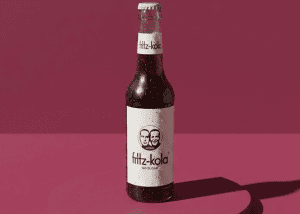 Botella de Fritz-Kola sin azúcar en fondo rosa.