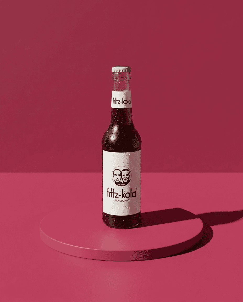 Fritz Kola No Sugar Candela Rolls Studio 2 Botella de Fritz-Kola sin azúcar en fondo rosa.