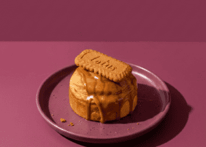 Postre de caramelo con galleta en plato rosa sobre fondo rosa.