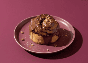 Postre de chocolate con toppings en plato rosa sobre fondo rosa.
